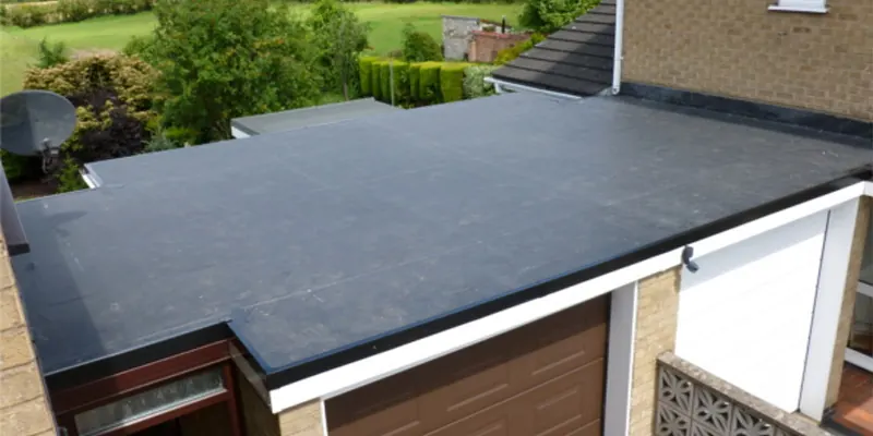 A finished dark flat roof on a one-storey addition beside a brick house